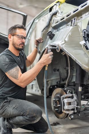 Technician performing dent repair on a vehicle panel